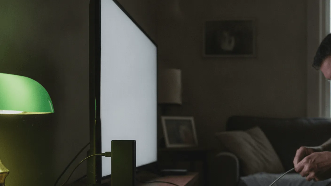 A Firestick 4K is half inserted into a television's rear HDMI port, with a man in the background.