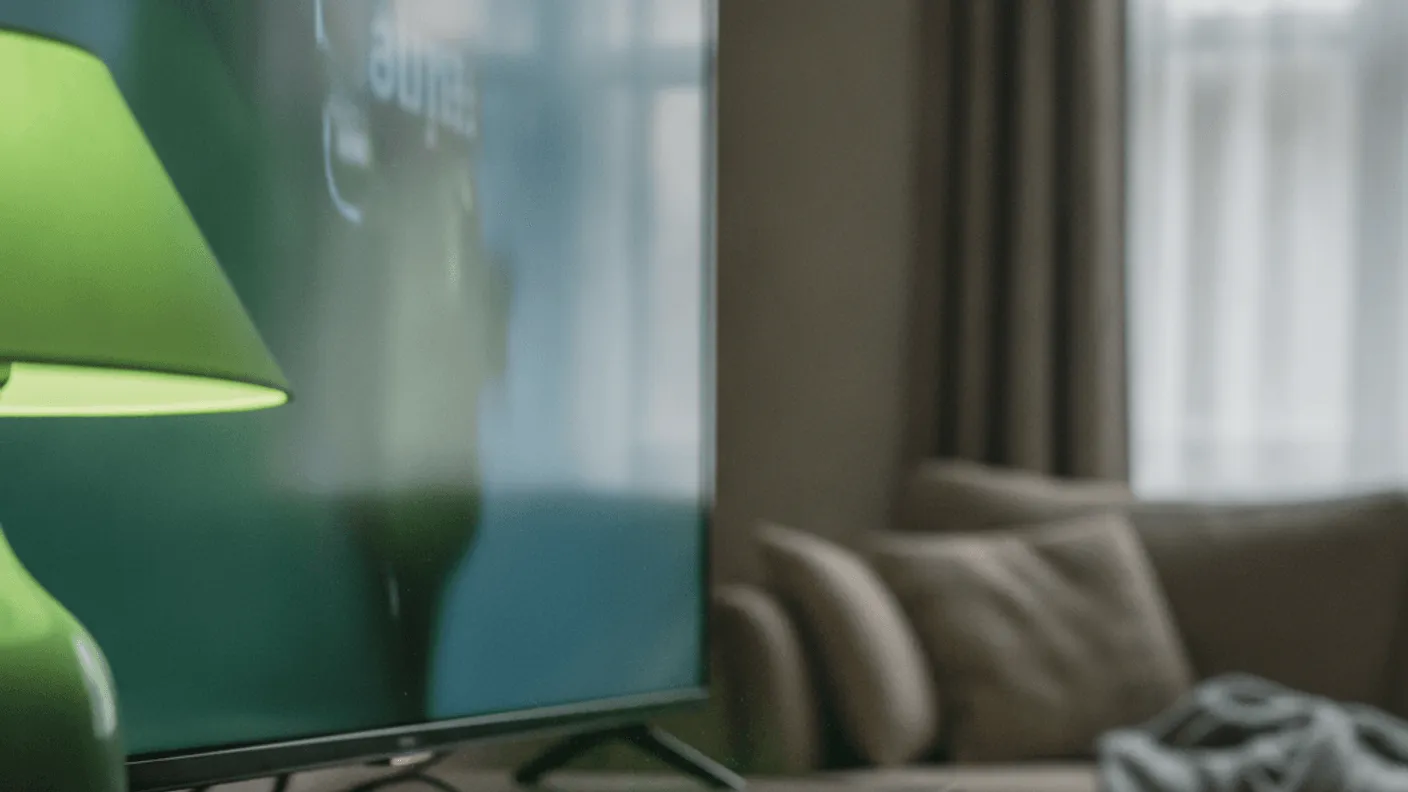 A streaming device is half-plugged into a TV, cables loose, with a man's hands holding a cable.